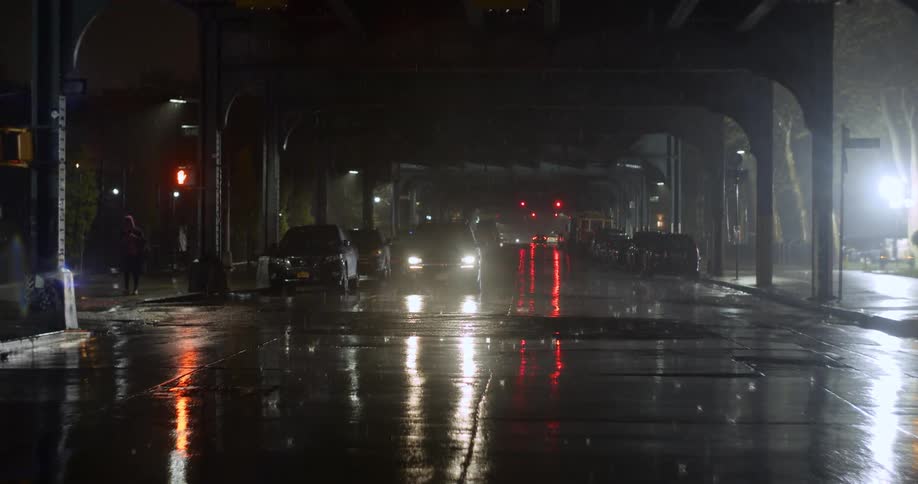 A vehicle sits in the middle of a city road while its raining