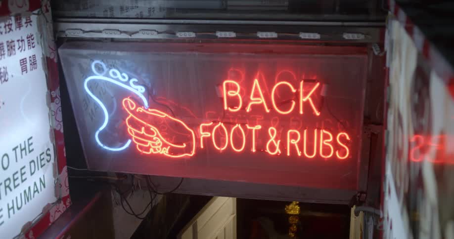 Neon sign advertises back and foot rubs in stairwell