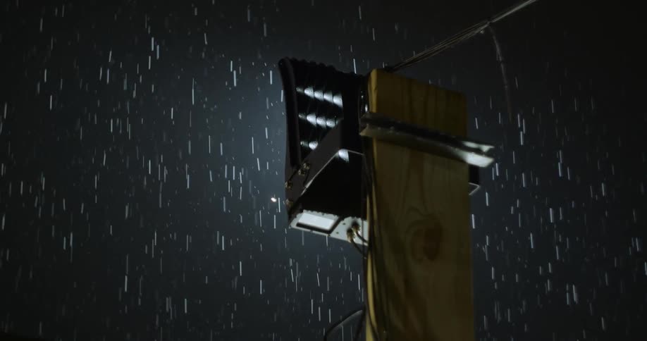 A streetlight shining at night while its raining