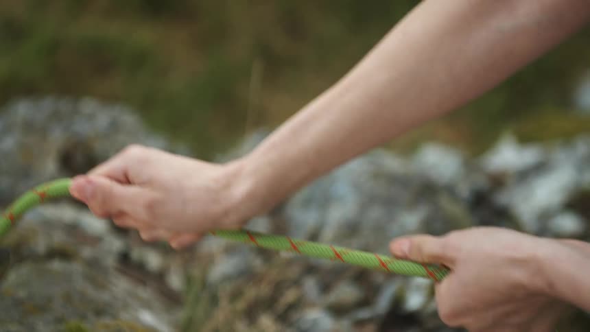A person pulls a green rope outdoors