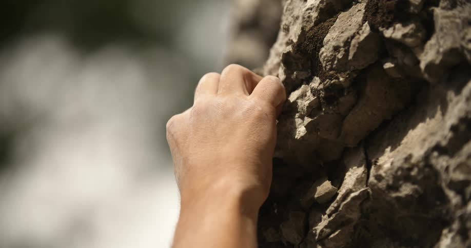 Climber holds onto a rock wall and accidentally breaks the rocks with his hands