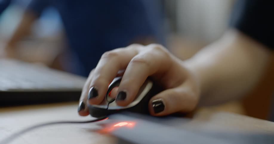 Woman with painted nails uses and clicks a computer mouse