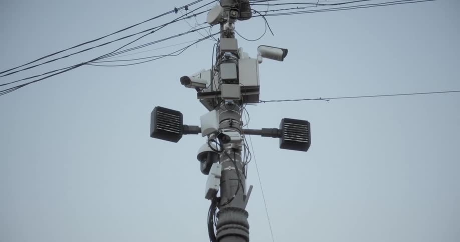 Cameras lamps and solar panels occupy pole under power lines