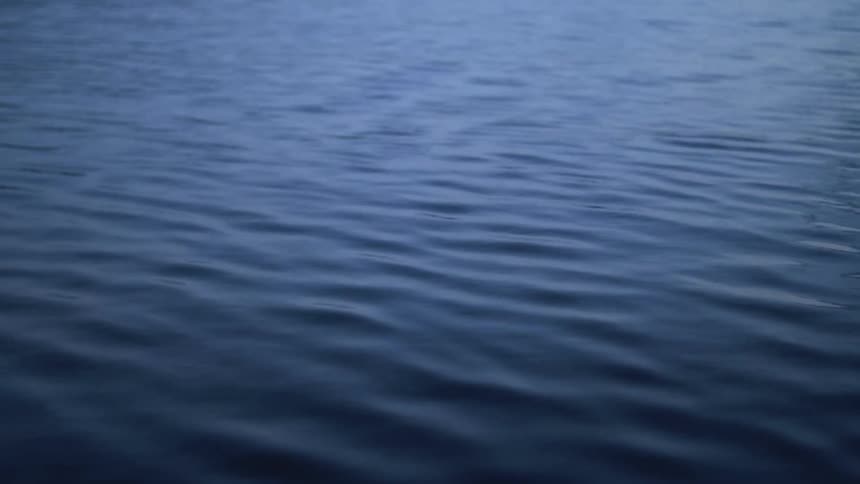 An ocean with some light reflecting off of rippling water