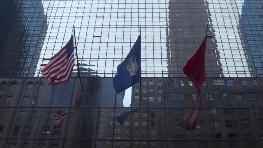 Big flags waving in the glass facade of a building in a big city