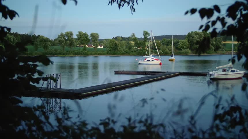 Boats anchored around a pier in the calm waters of a lake