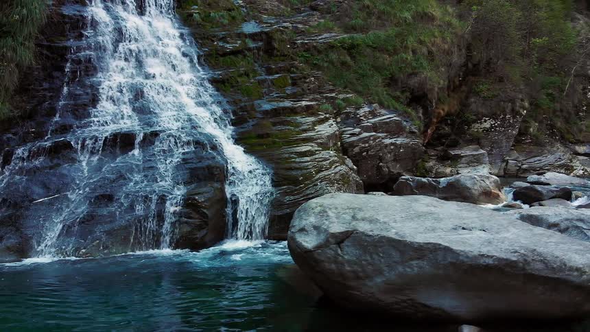 A waterfall spills down rocks and into a body of water