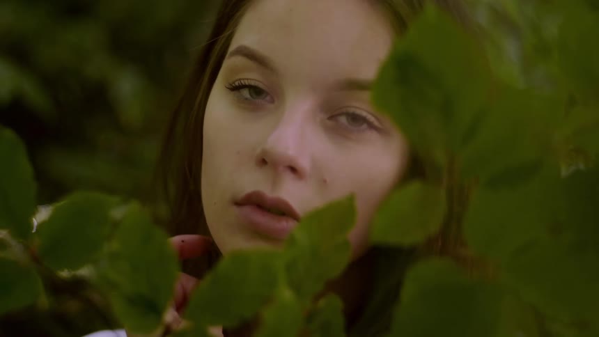 Woman stands among plants running hand through hair