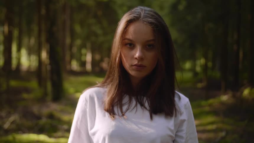 Woman walks on a trail in the forest and turns to look to her left