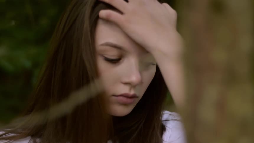 Young woman walking in forest brushes hair out of face
