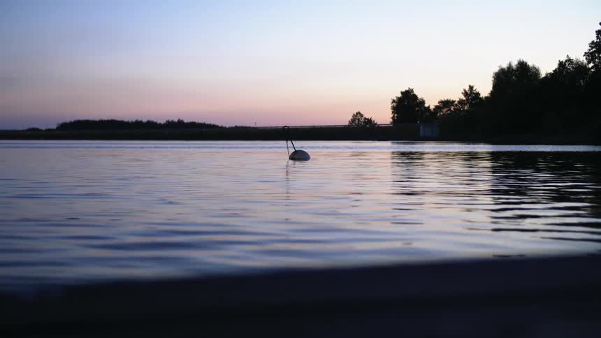 Boat floats in the lake at dusk