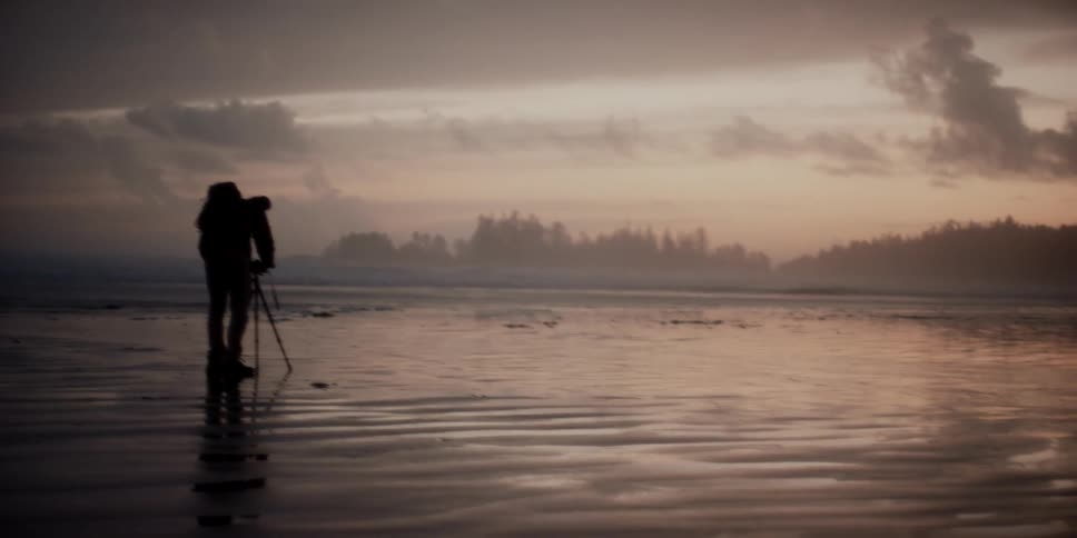A photographer sets up their camera in the dim sunlight