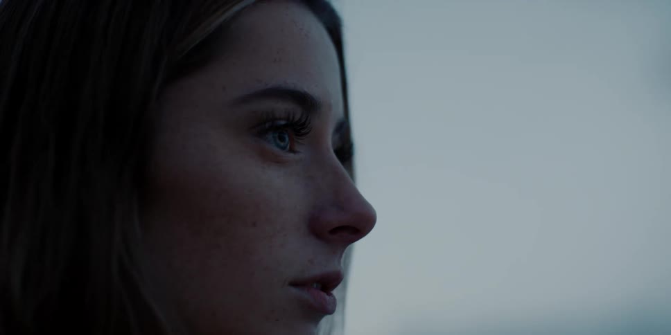 A white woman stands outdoors and looks into the distance