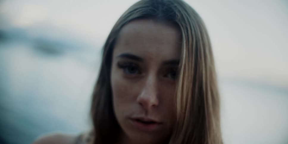 Zoom in and close up of the face of a young woman wearing a bikini in the beach