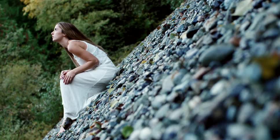 A teenager sitting on a bed of rocks