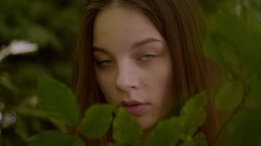 A woman is partially obscured by a leafy branch