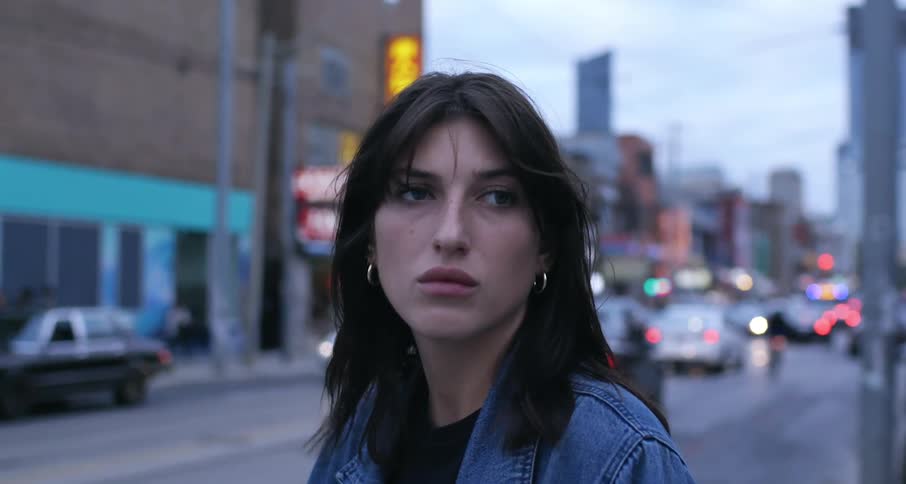 Young woman stands at a busy intersection at dusk