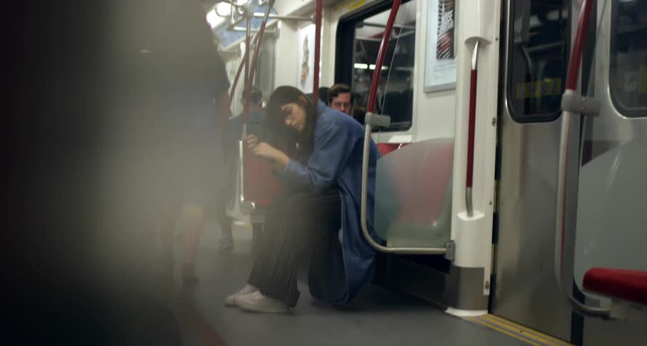 A sad young white woman sits in a subway car