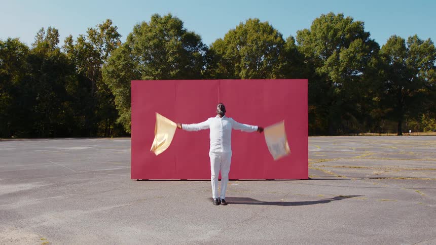 A man is dancing in front of a red board