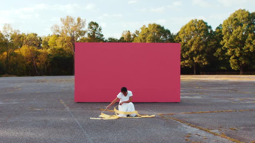 Young woman with dance ribbons in front of red billboard in parking lot