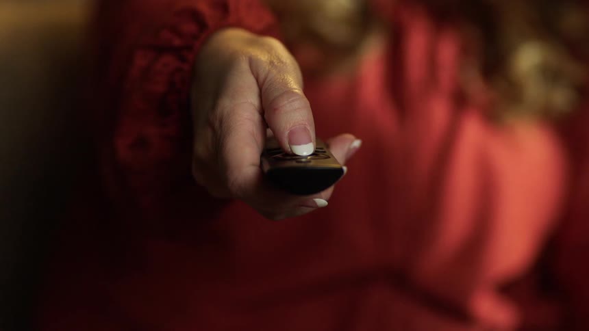 Female hand holding out a tv remote