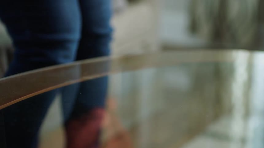 Female hand picking up tv remote from glass coffee table