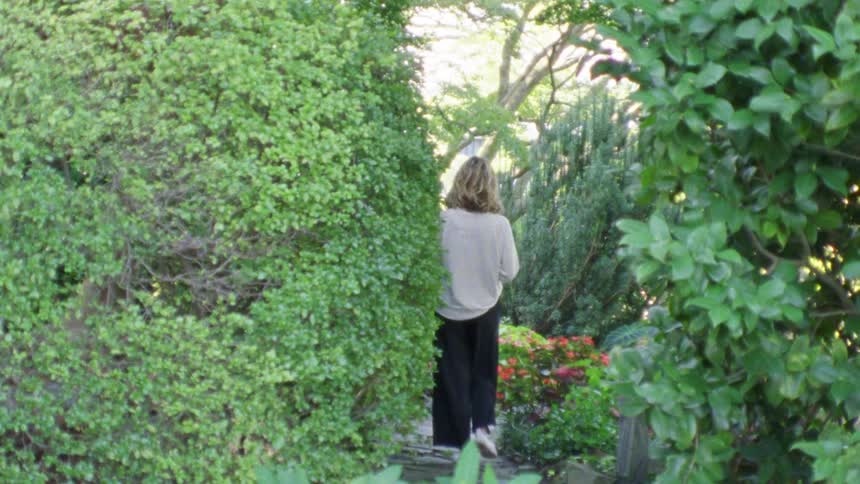 Woman walks on a stone path through a garden