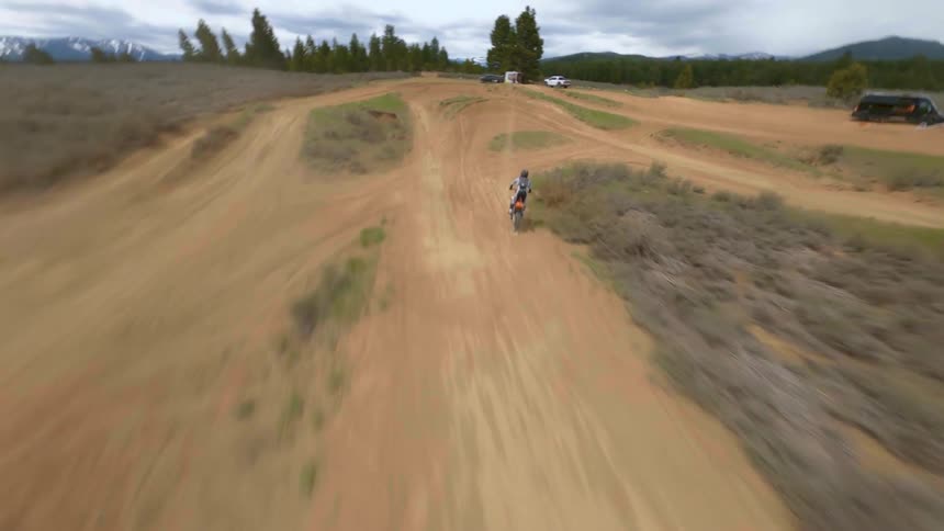 A person riding a motorcycle races around a dirt track
