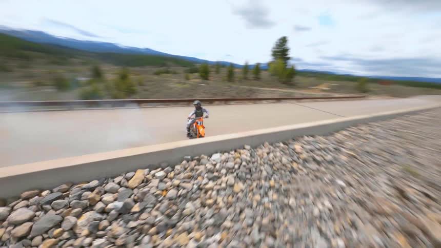 Aerial view of a motocross motorcycle burning tire rubber on a road near a lake
