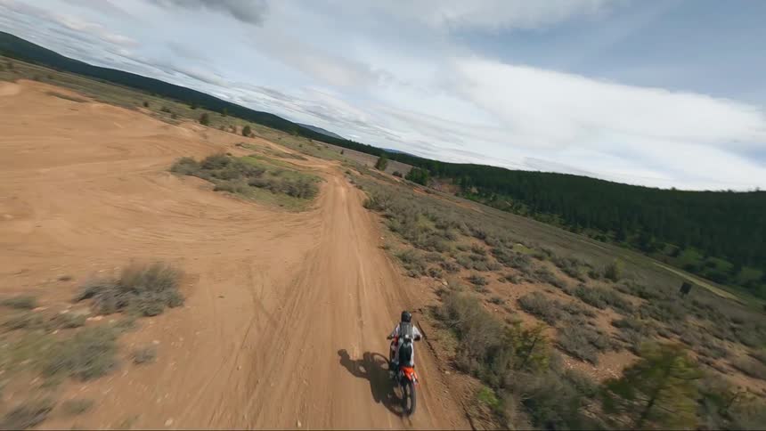 A person rides a dirt bike on a dirt road in a very rural area