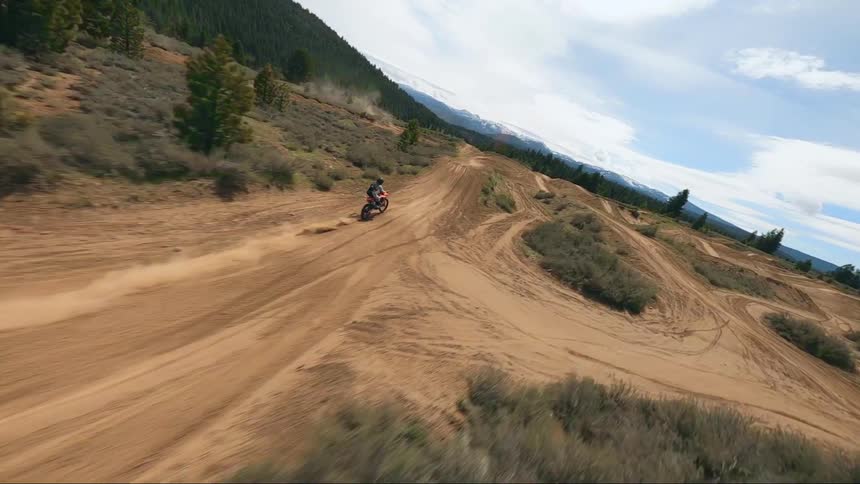 Aerial view of a man driving a motocross offroad motorcycle on a dirt track