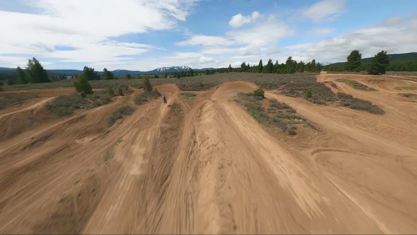 A bicyclist rides a dirt bike along the lines in a dirt field