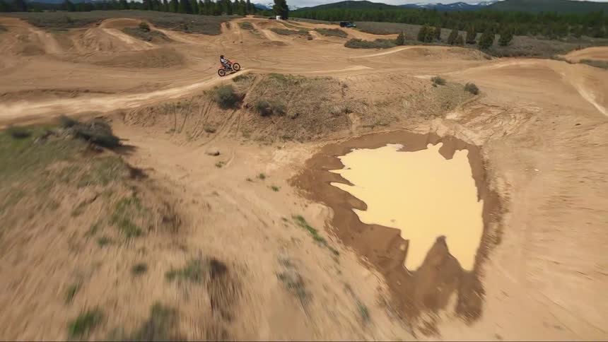 Aerial view of man driving motocross motorcycle on a dirt track