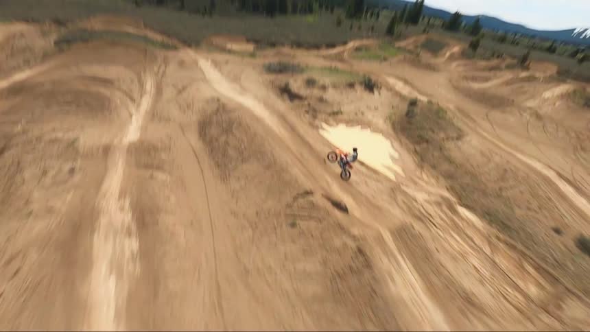 A person jumps on the dirt hill with his dirt bike