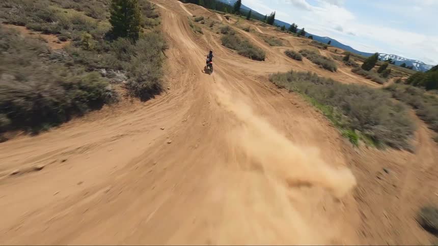 A person jumps a large dirt hill on the bike