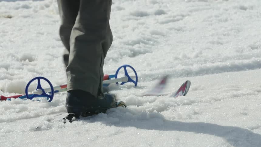 A kid playing around with skis then picking polls up with their hands