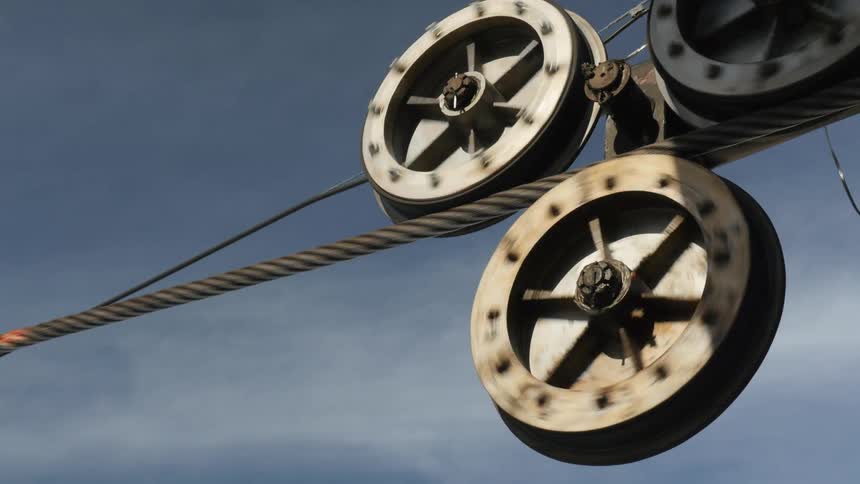 Turning wheels of a ski lift moving a metal cable