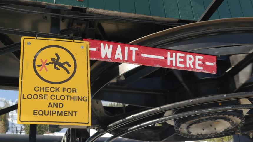 Warning signs next to heavy equipment at a ski resort