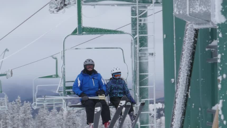 People ride a chair lift at a ski mountain resort