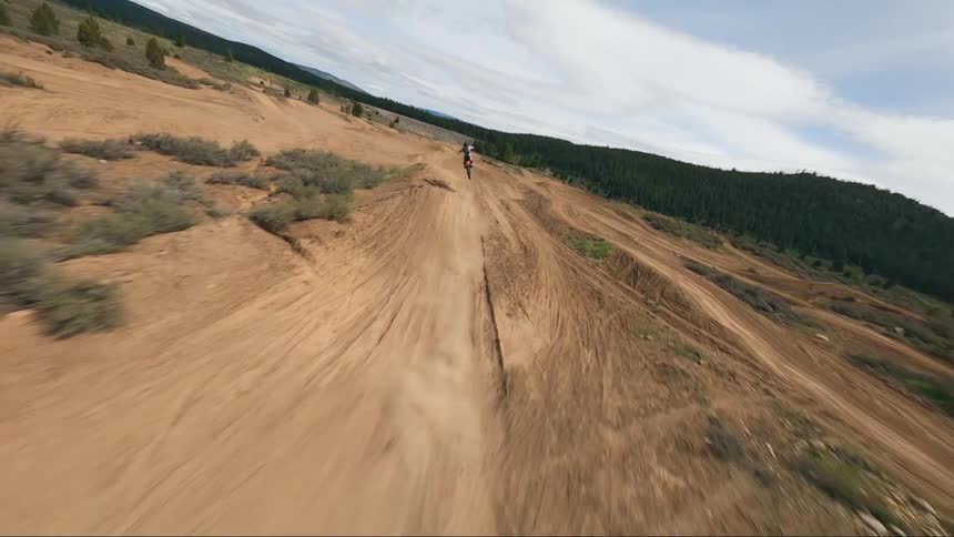 A person in a dirt bike riding and jumping on a dirt obstacle course