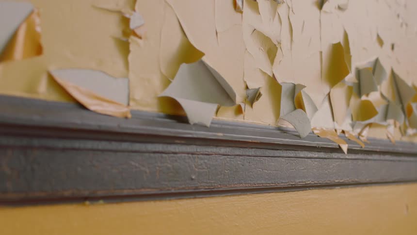 Peeling and flaking mustard yellow paint on wall