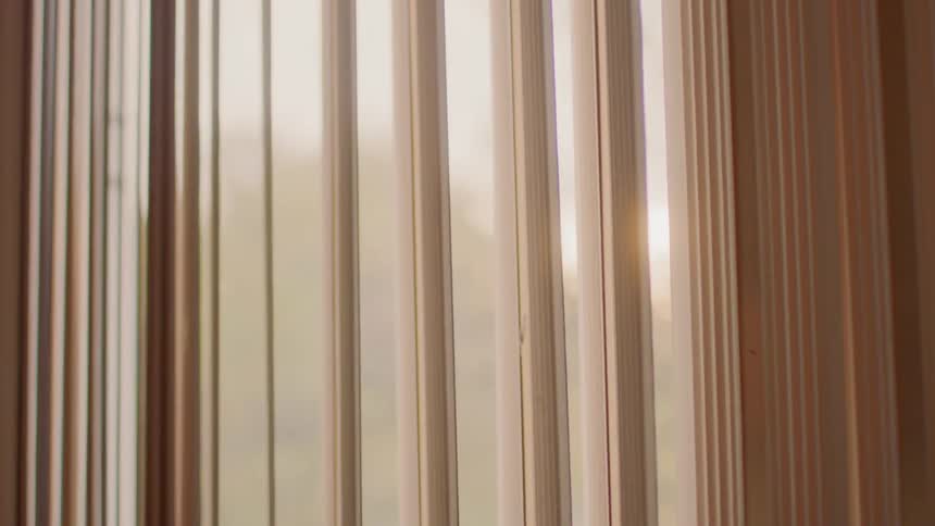 Sunlight filters through the brown curtains at sunset