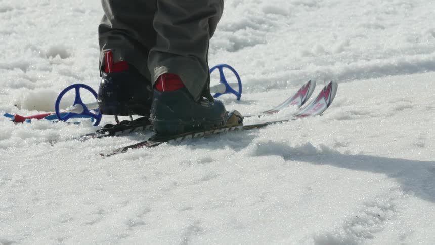 A child steps into his skis
