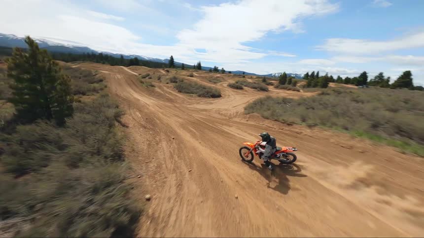 A person rides a dirtbike around a track aerial