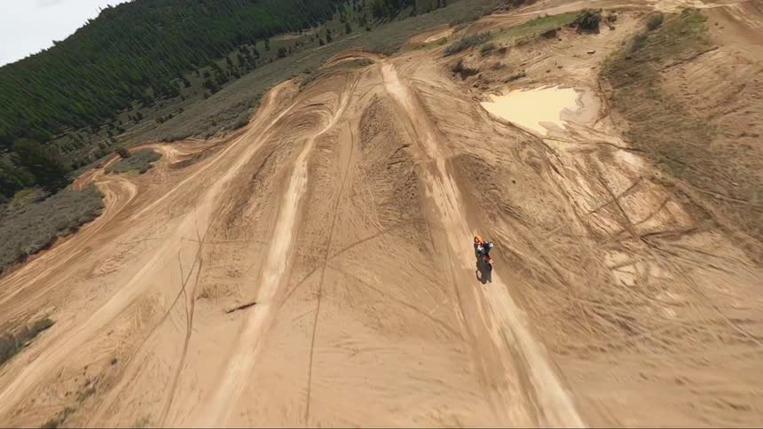 A person is riding their motorcycle on a dirt track near some mountains