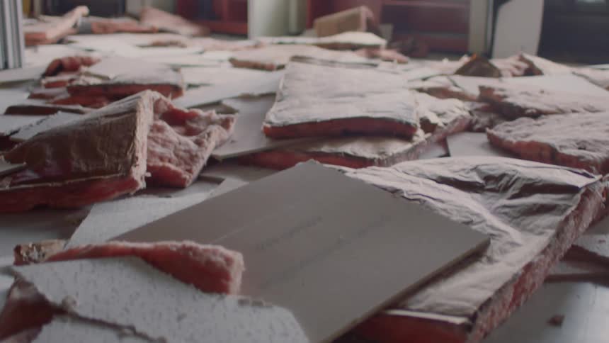 Sheetrock insulation and ceiling tiles lay scattered across the floor near shelves