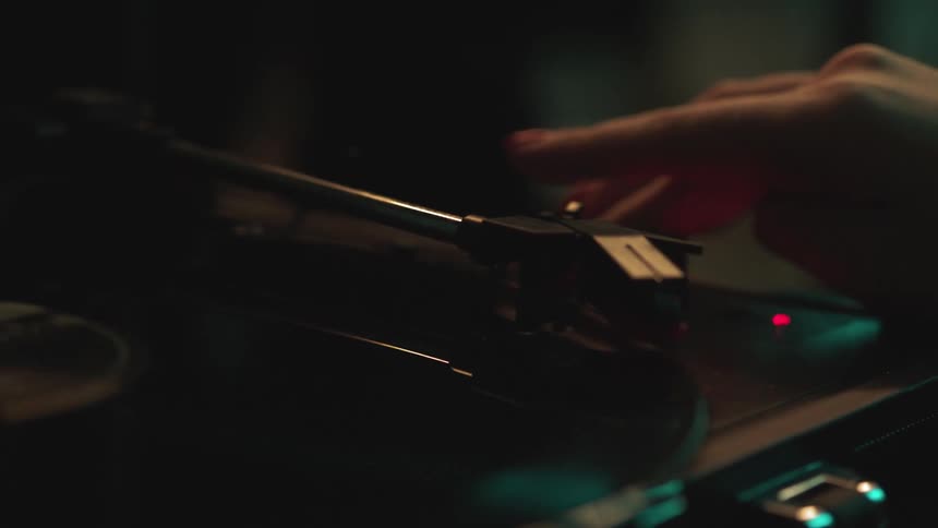 Hand turns on a record player causing the record to start spinning around