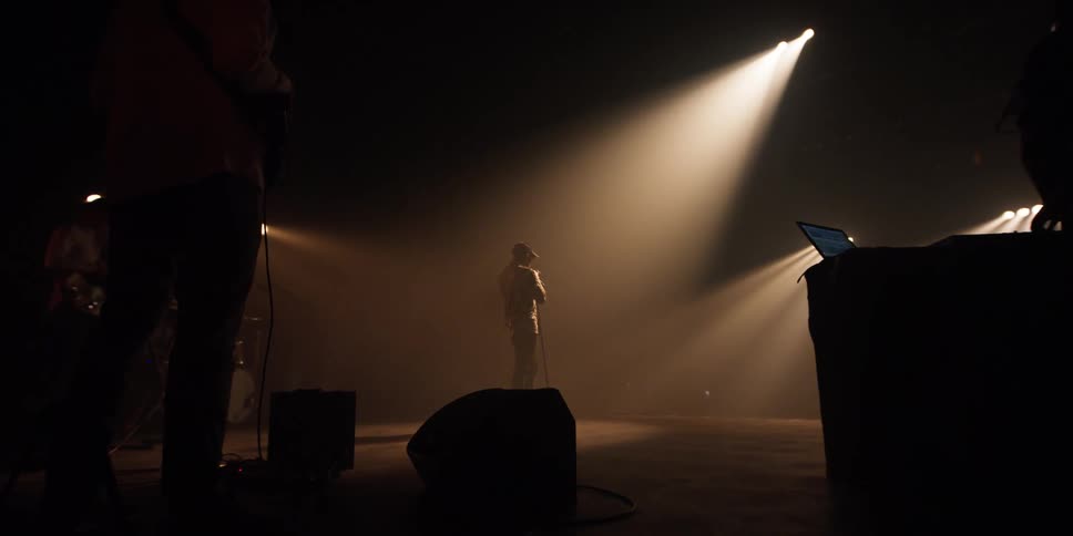 Singer stands under the spotlight on stage with a microphone