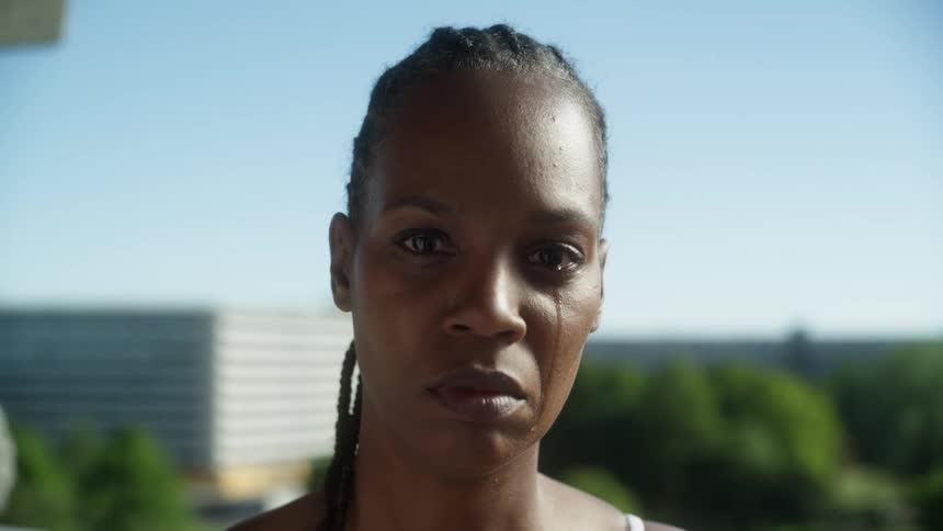 A portrait of a black woman with ponytail shedding tears