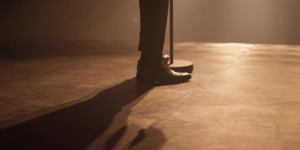 A person stands near a microphone stand on a stage